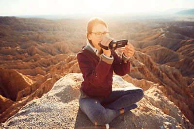 woman on a mountaintop with camcorder pointed at the view